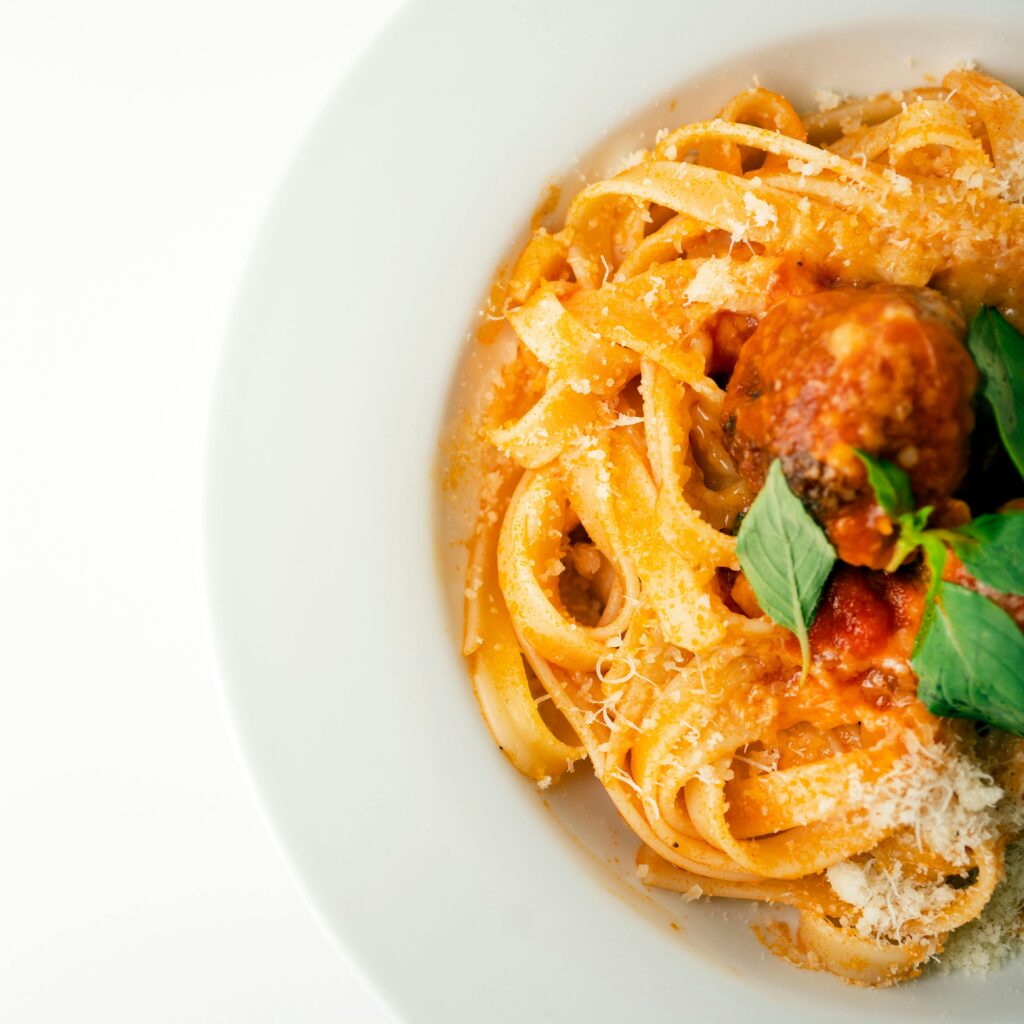 Close-up food photography of fettuccine with meatballs, cheese, and herbs in Tehran, Iran.